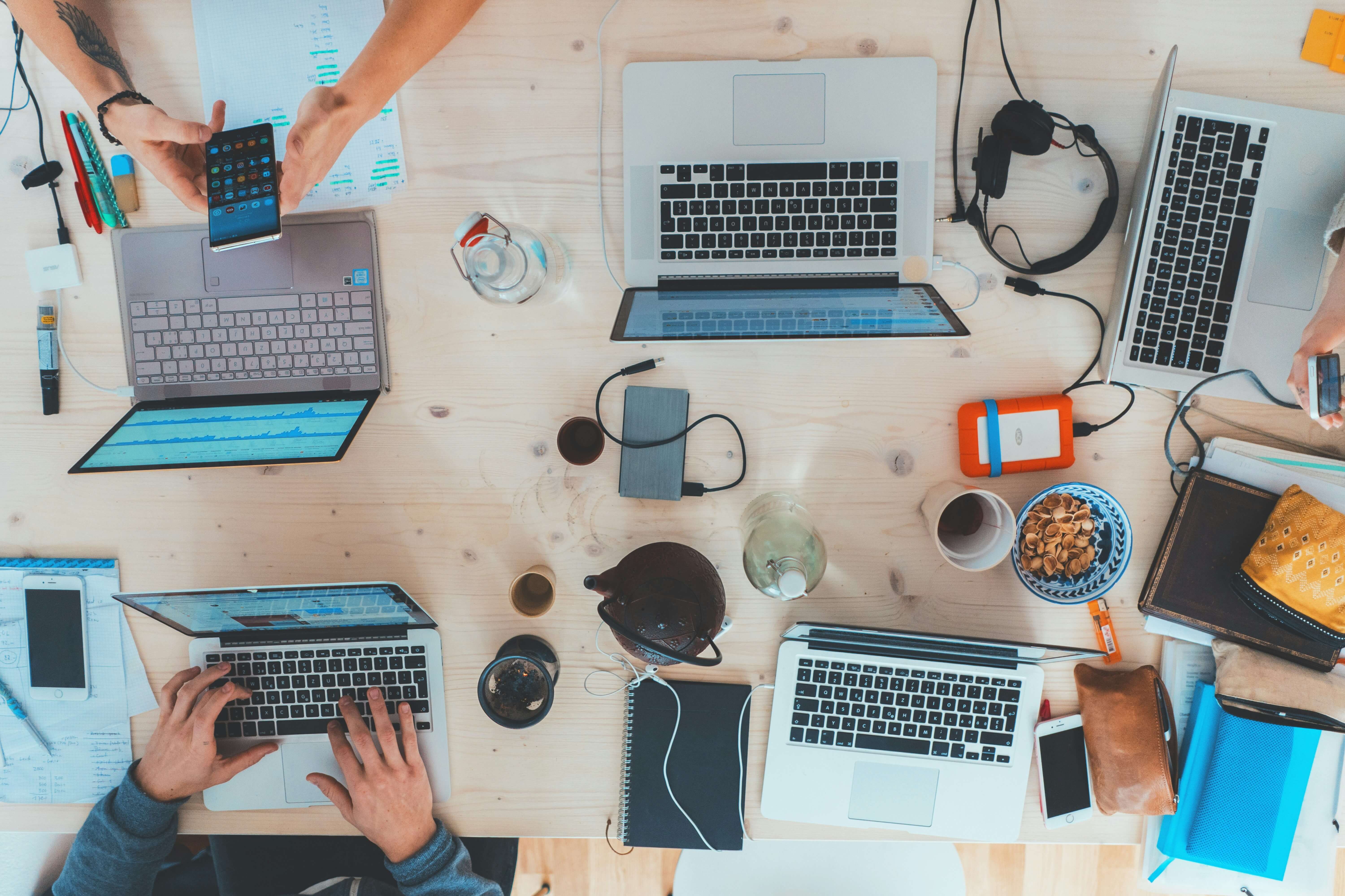 A diverse group of individuals collaborating at a table, each focused on their laptops, engaged in productive work.